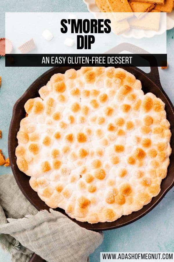 Cast iron skillet on a blue background filled with s'mores dip with toasted marshmallows on top with a text overlay.
