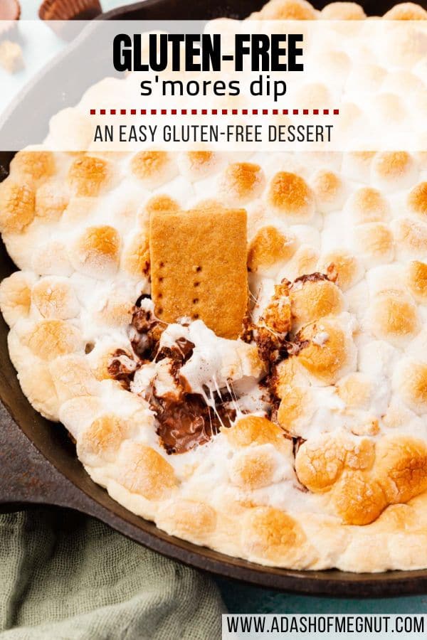 A graham cracker dipped into s'mores dip in a cast iron skillet.