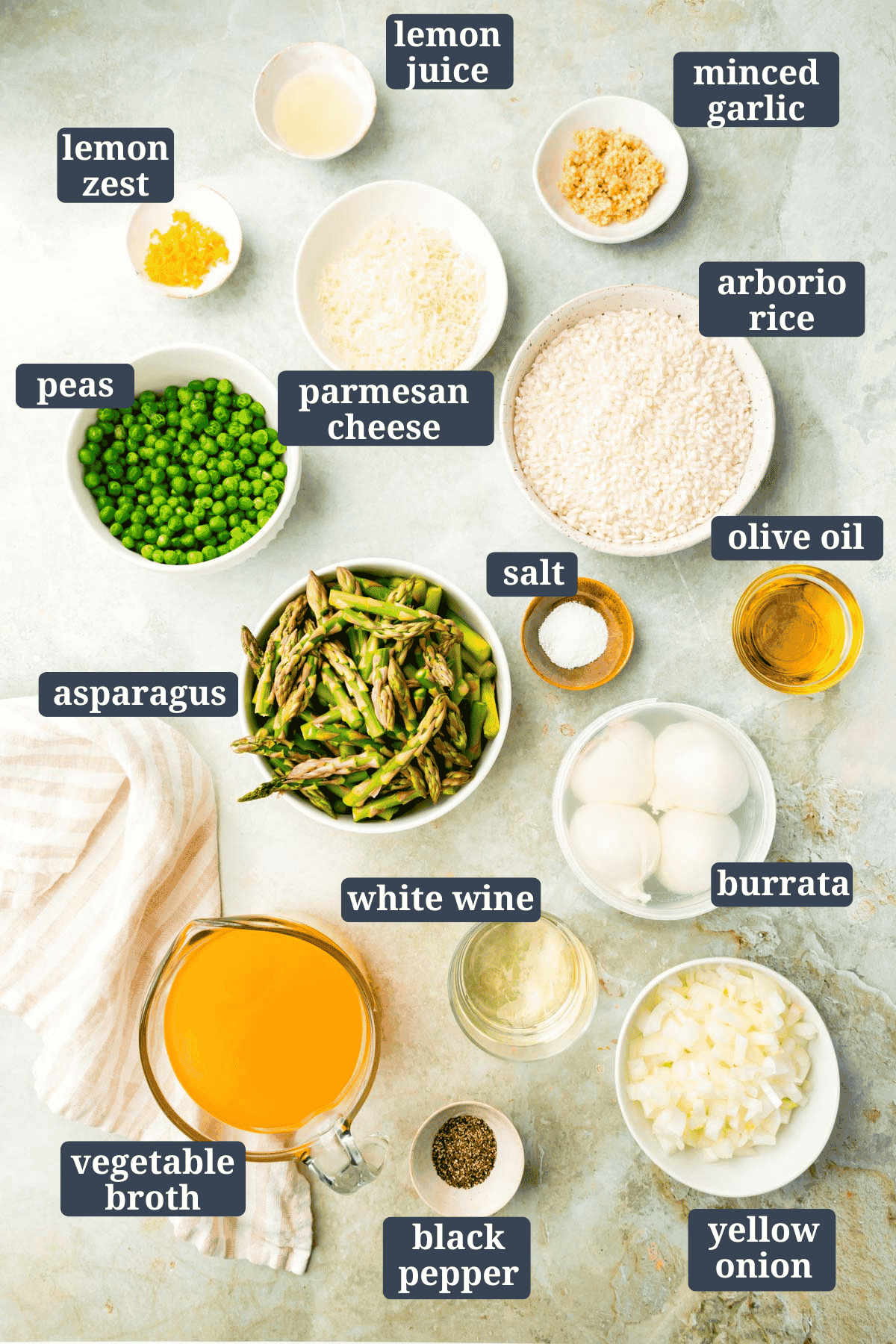 Small bowls on a table filled with ingredients to make pea and asparagus risotto with burrata with text overlay.