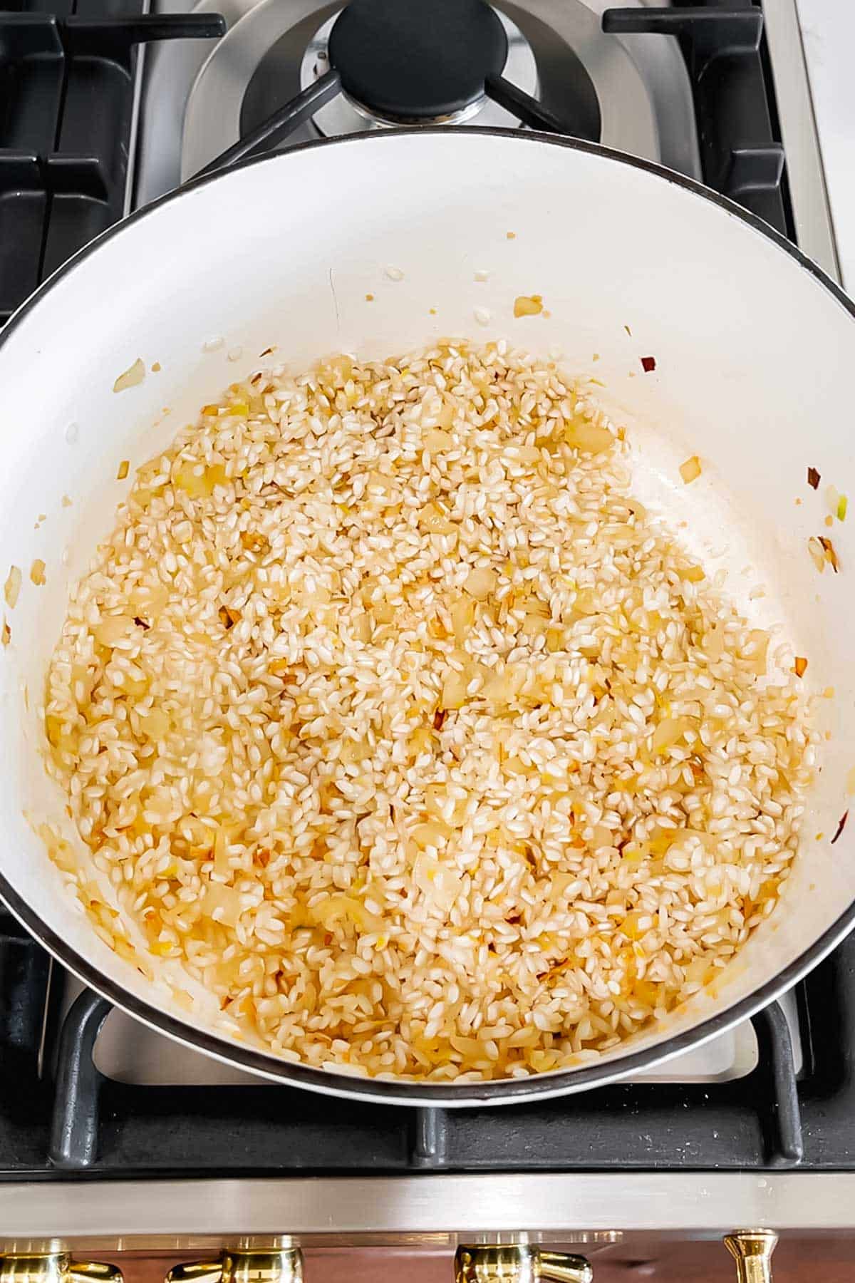 Toasted arborio rice and diced onion sautéed in a dutch oven.