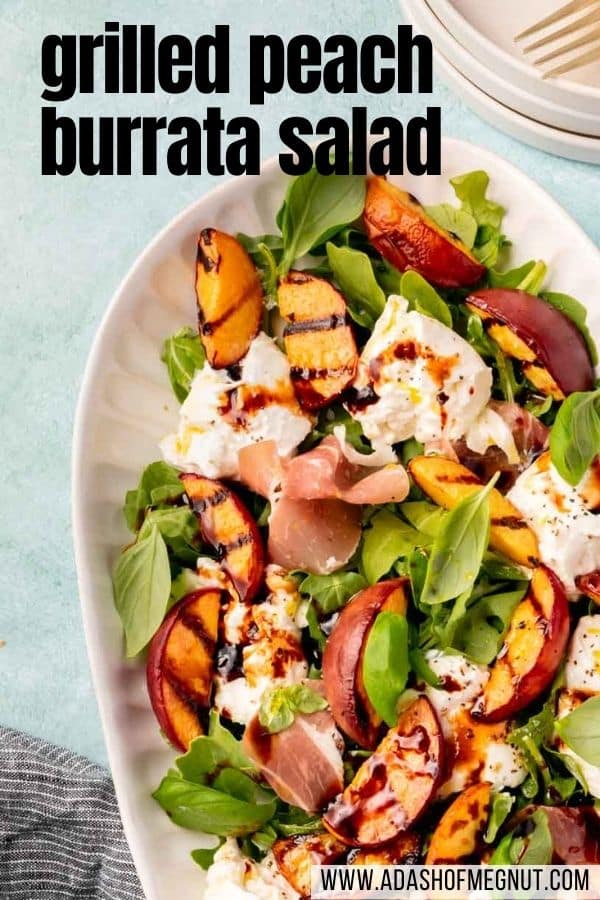 An oval platter with grilled peaches, burrata, arugula, basil, prosciutto, balsamic glaze, and olive oil.