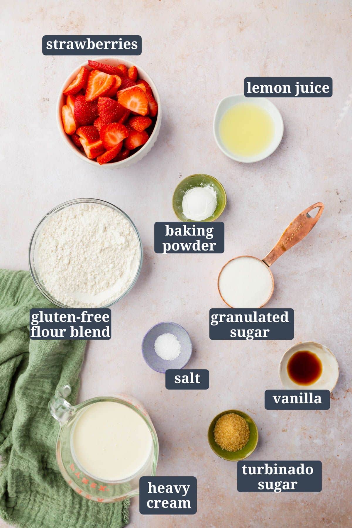 An overhead view of small bowls of ingredients to make gluten-free strawberry shortcakes with text overlays over each ingredient.