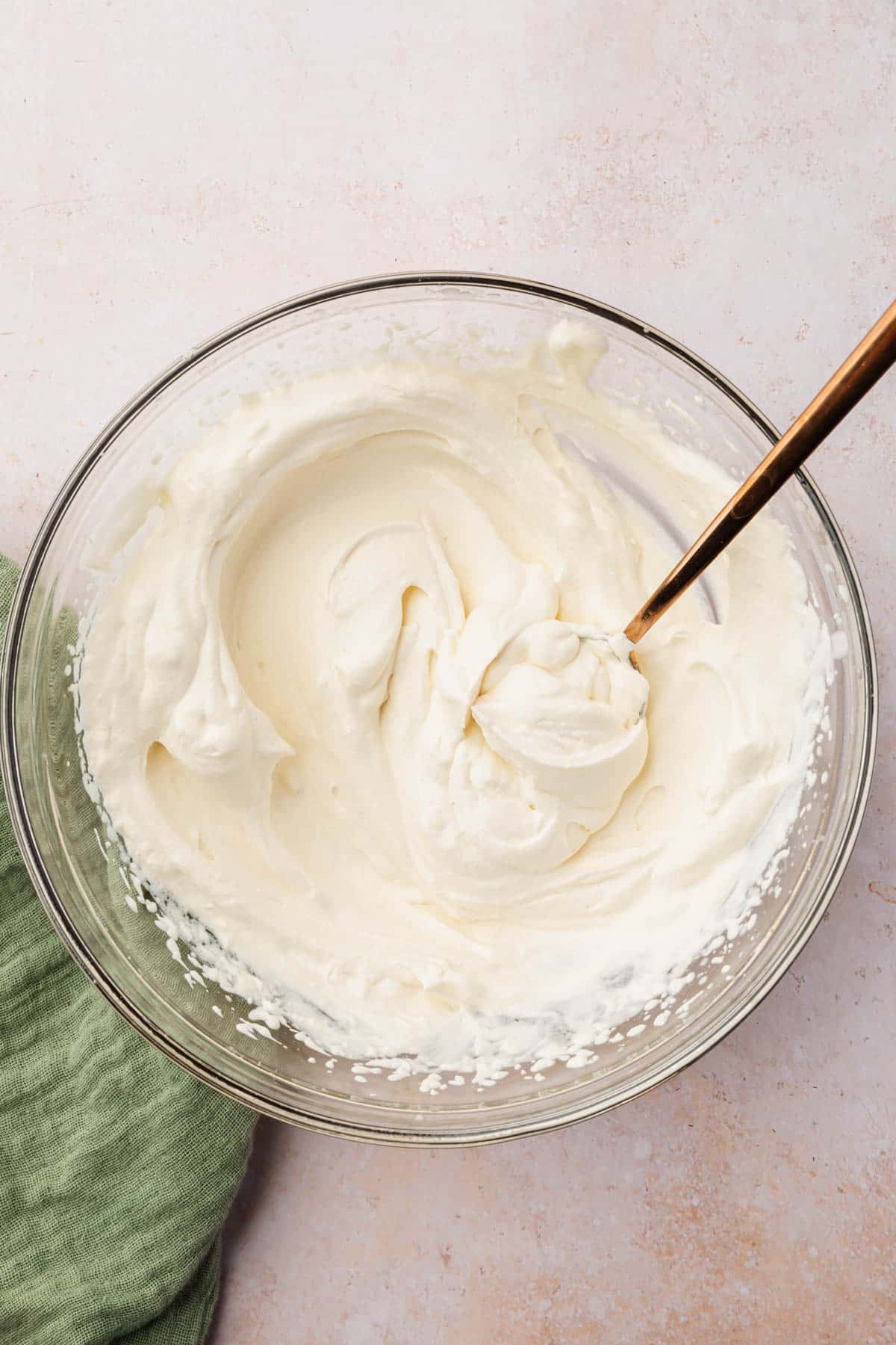 A bowl of fresh homemade whipped cream with a spoon in it.