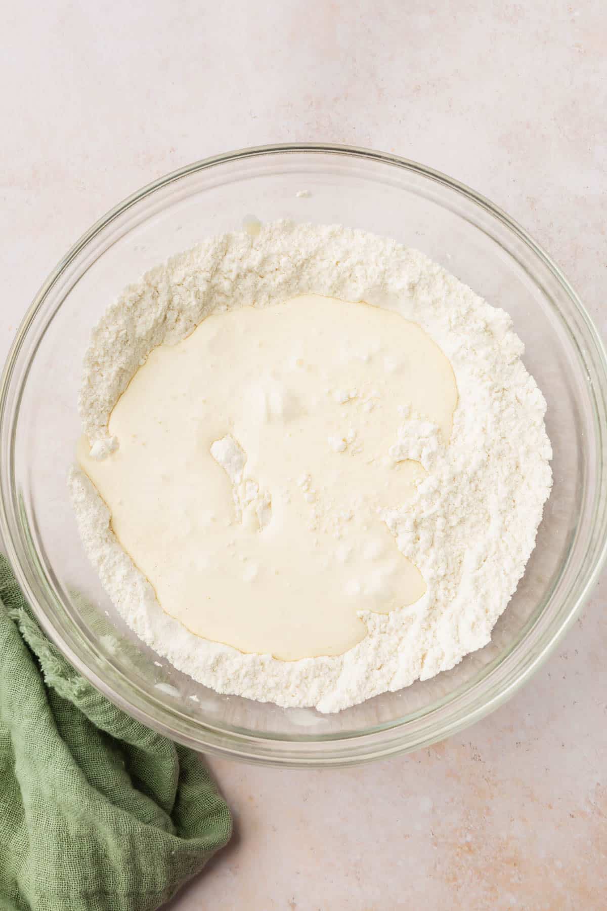 A glass mixing bowl with gluten-free flour blend and heavy cream unmixed.