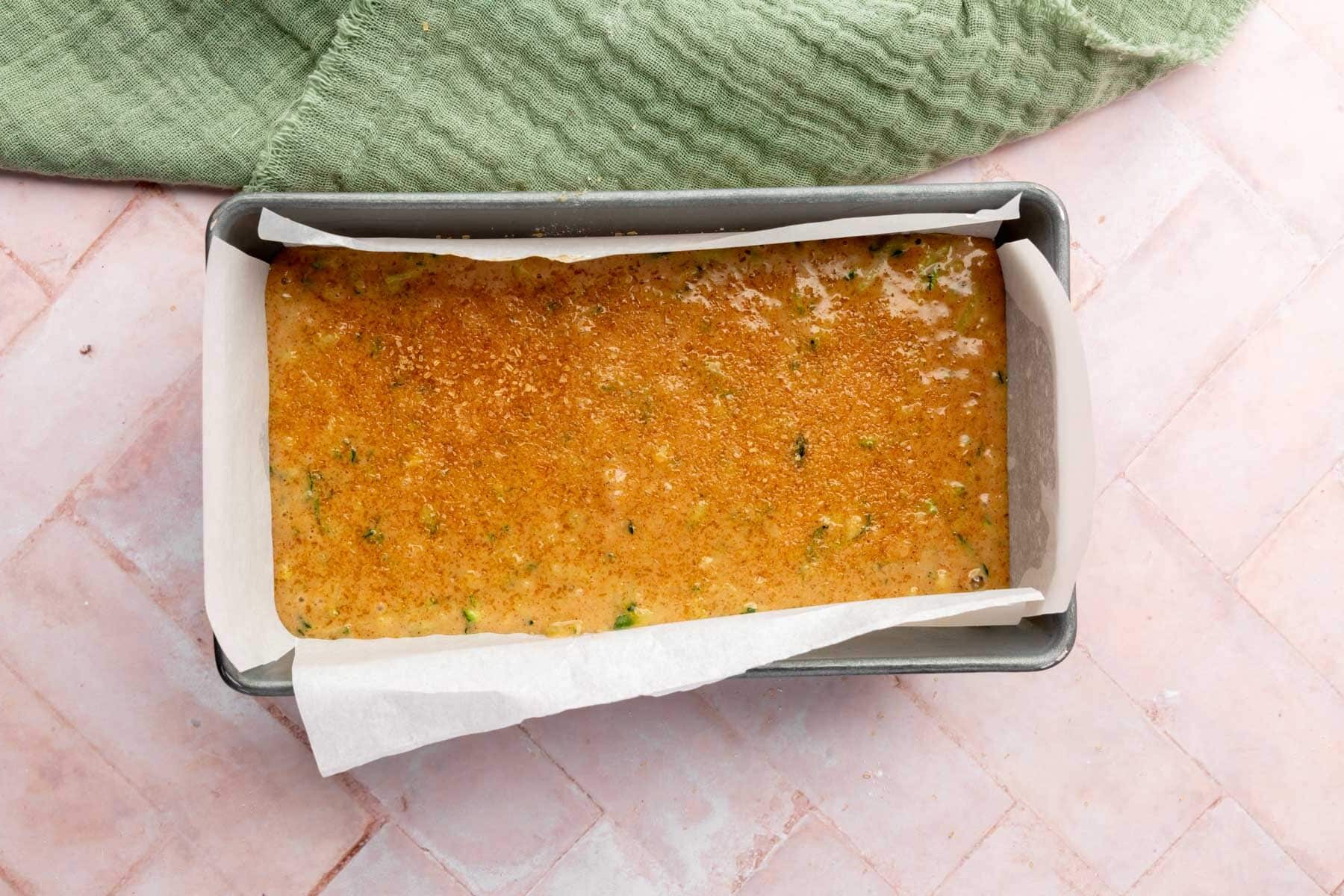 Gluten-free zucchini bread batter in a lined loaf pan before baking.