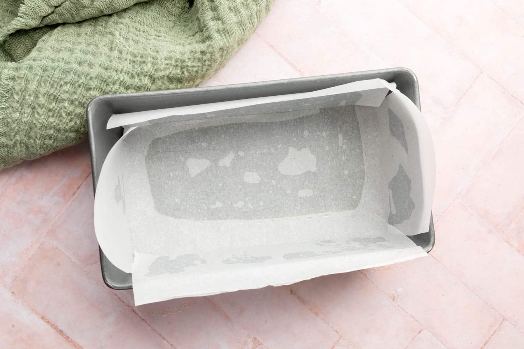 A metal loaf pan lined with parchment paper.