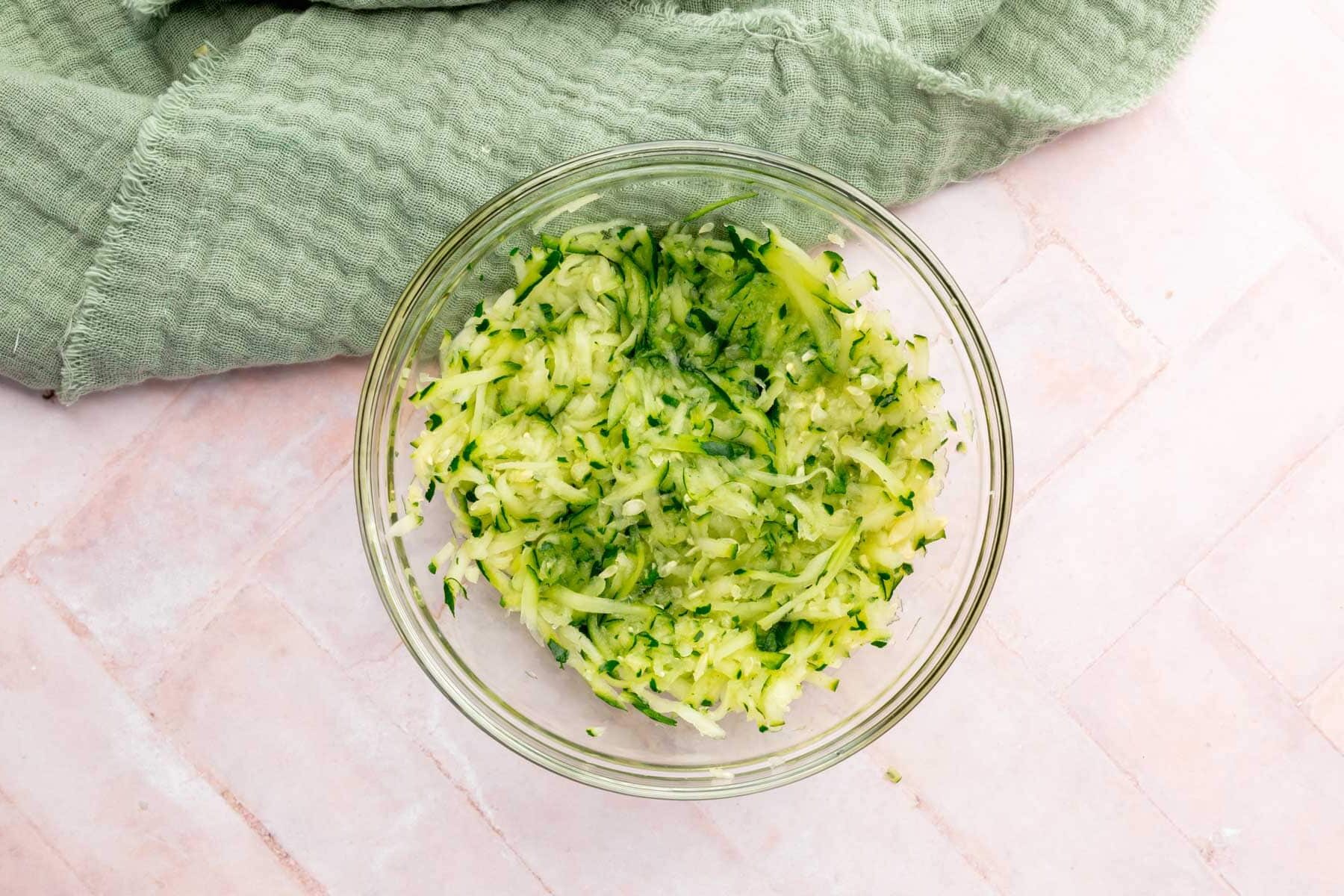 A small glass mixing bowl filled with grated zucchini.