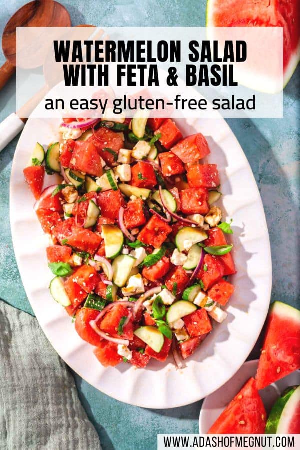 A large oval platter with watermelon salad with feta and basil on it with a text overlay.