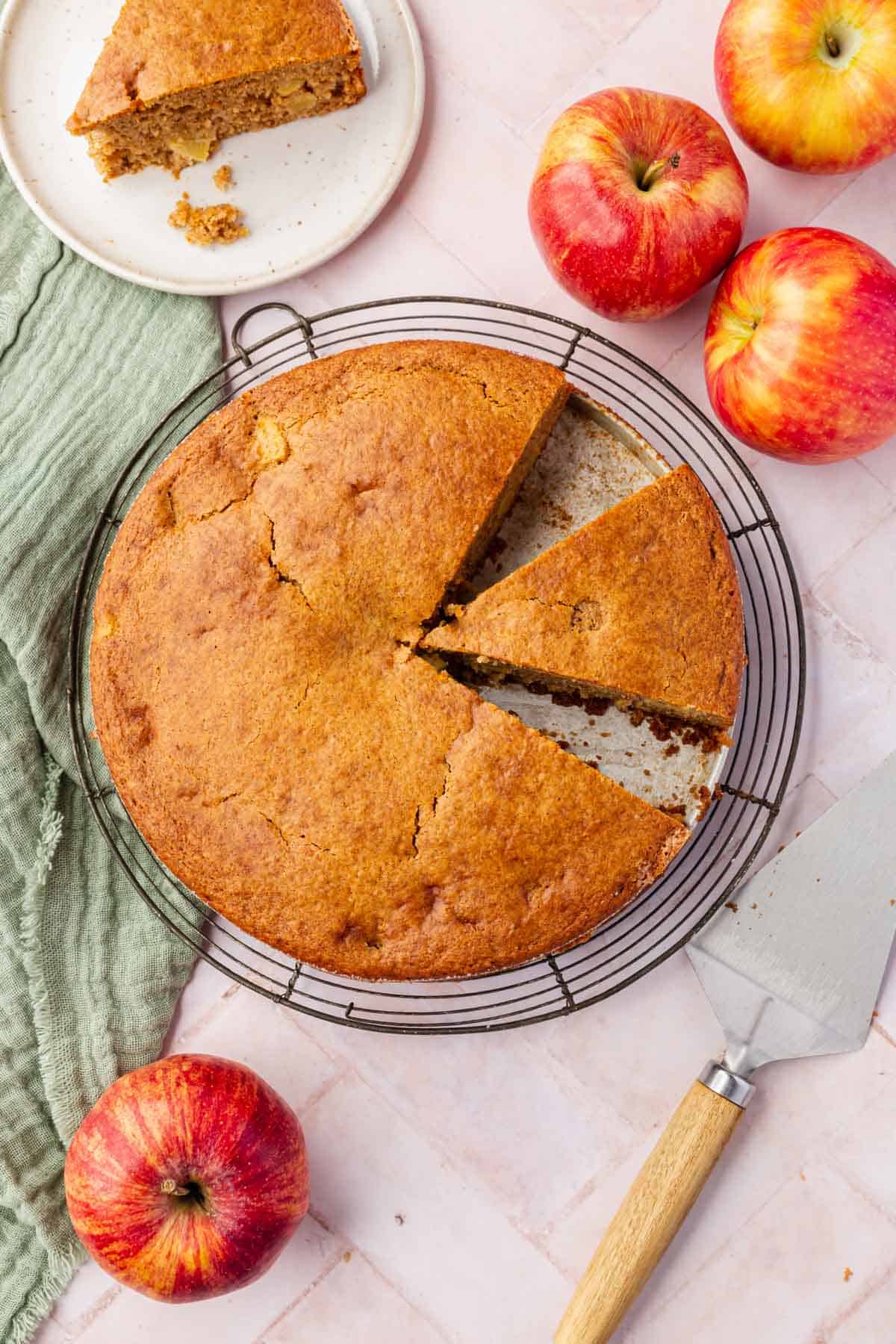 An overhead view of a round single-layer gluten-free apple cake with one slice cut from the cake.