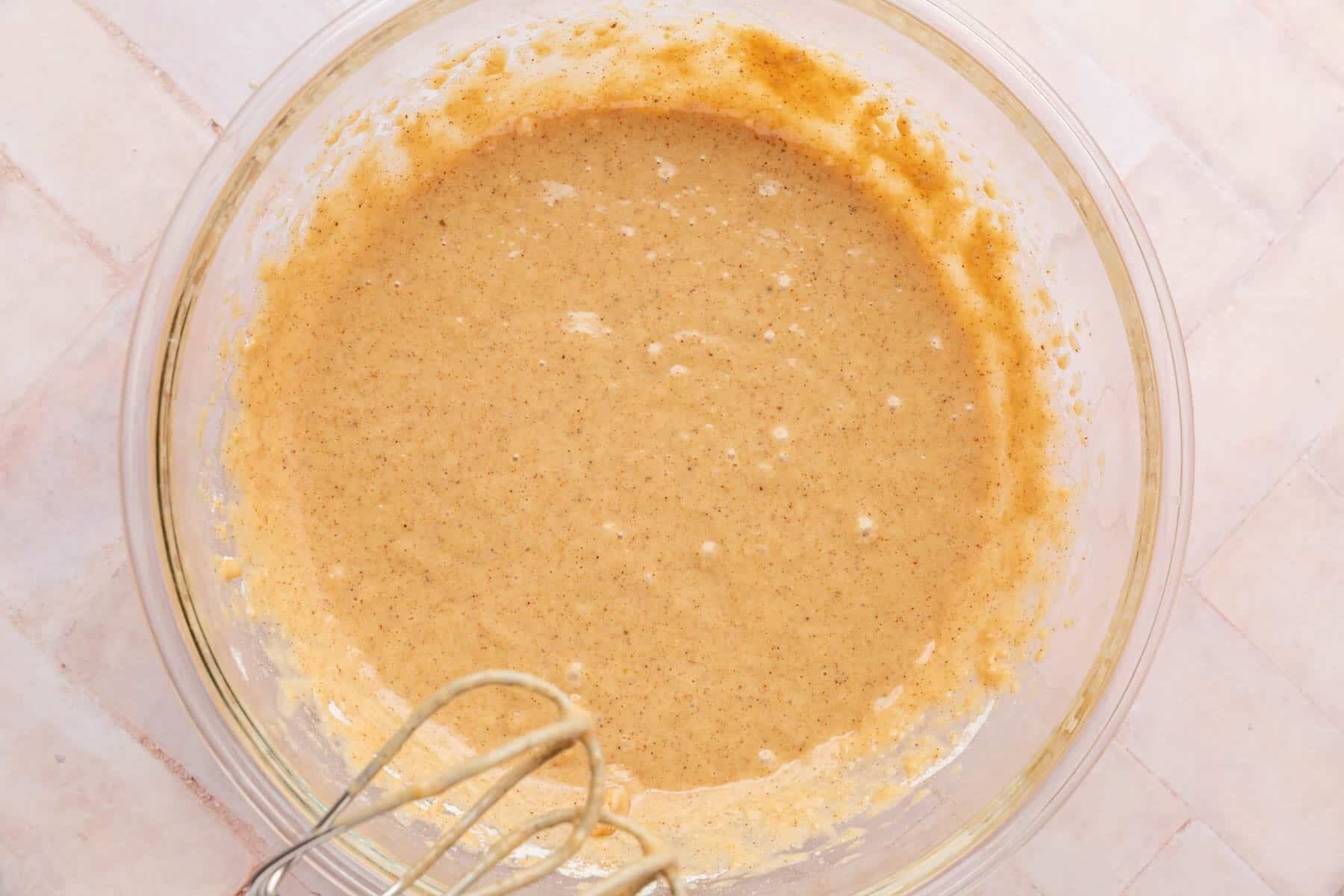 A glass mixing bowl with gluten-free spiced cake batter in it.