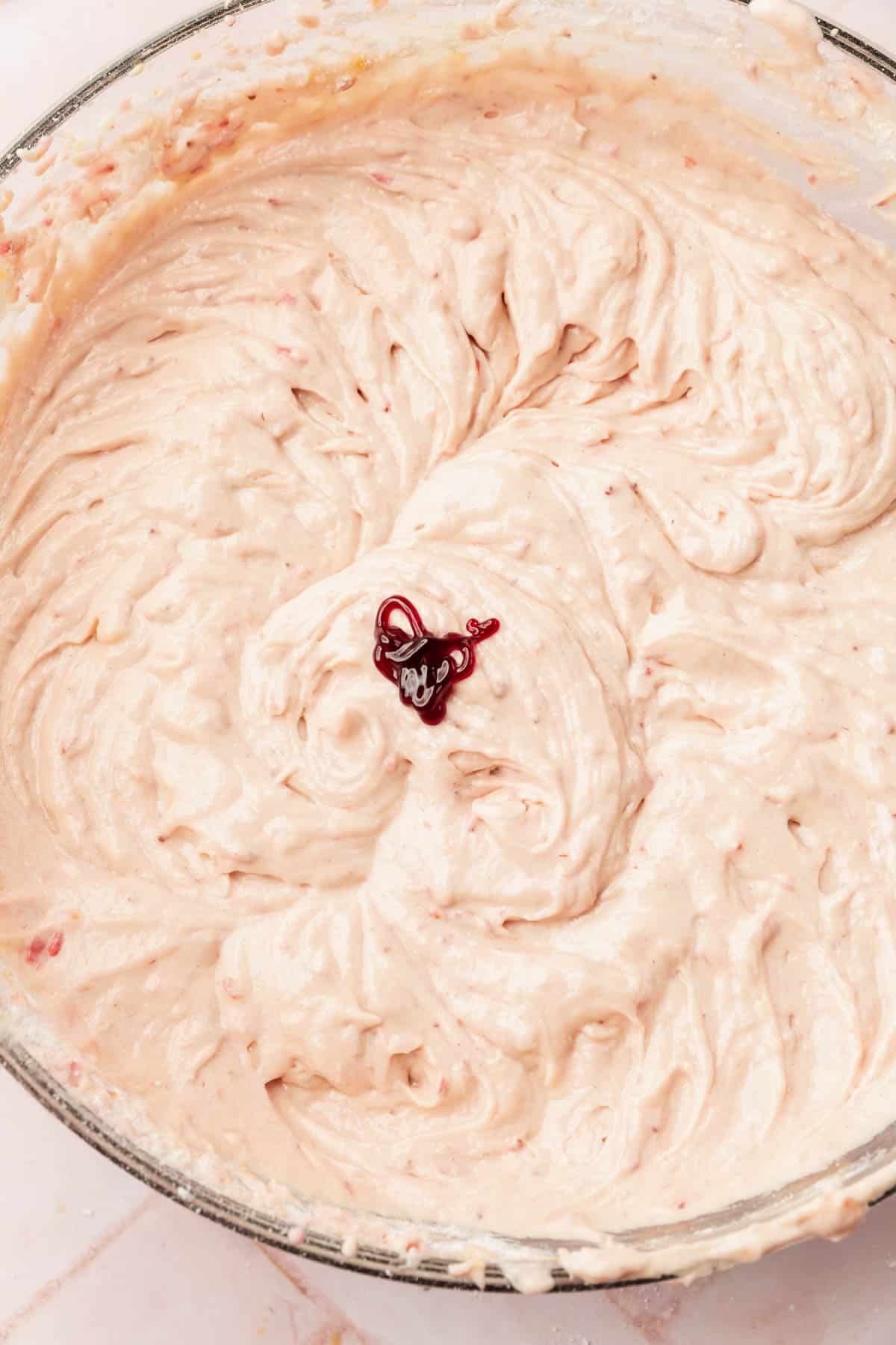 A large mixing bowl with gluten-free strawberry cake batter topped with a little red food coloring before mixing.