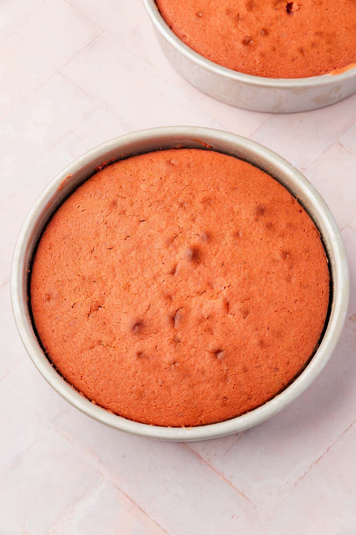 Baked strawberry cake in a round cake pan.