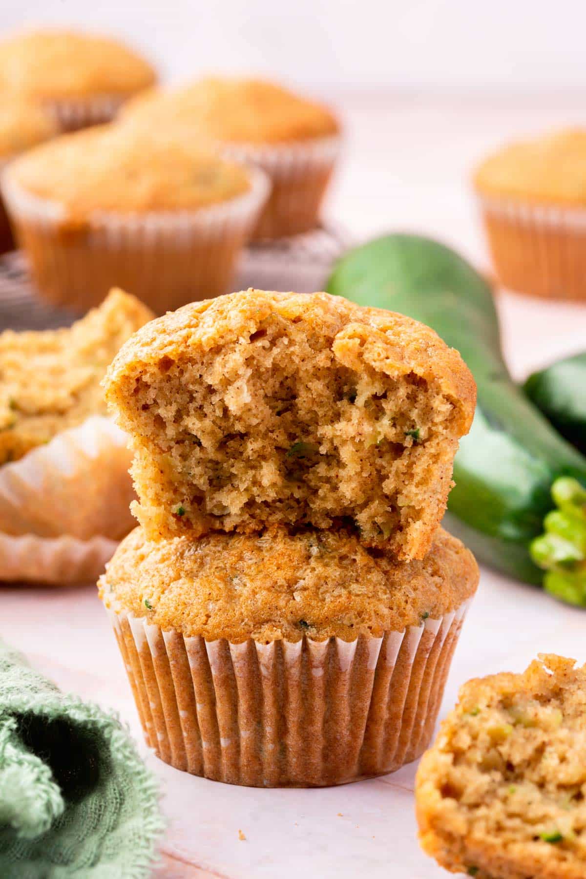 A gluten-free zucchini muffin with a bite taken out of it stacked on top of another zucchini muffin.