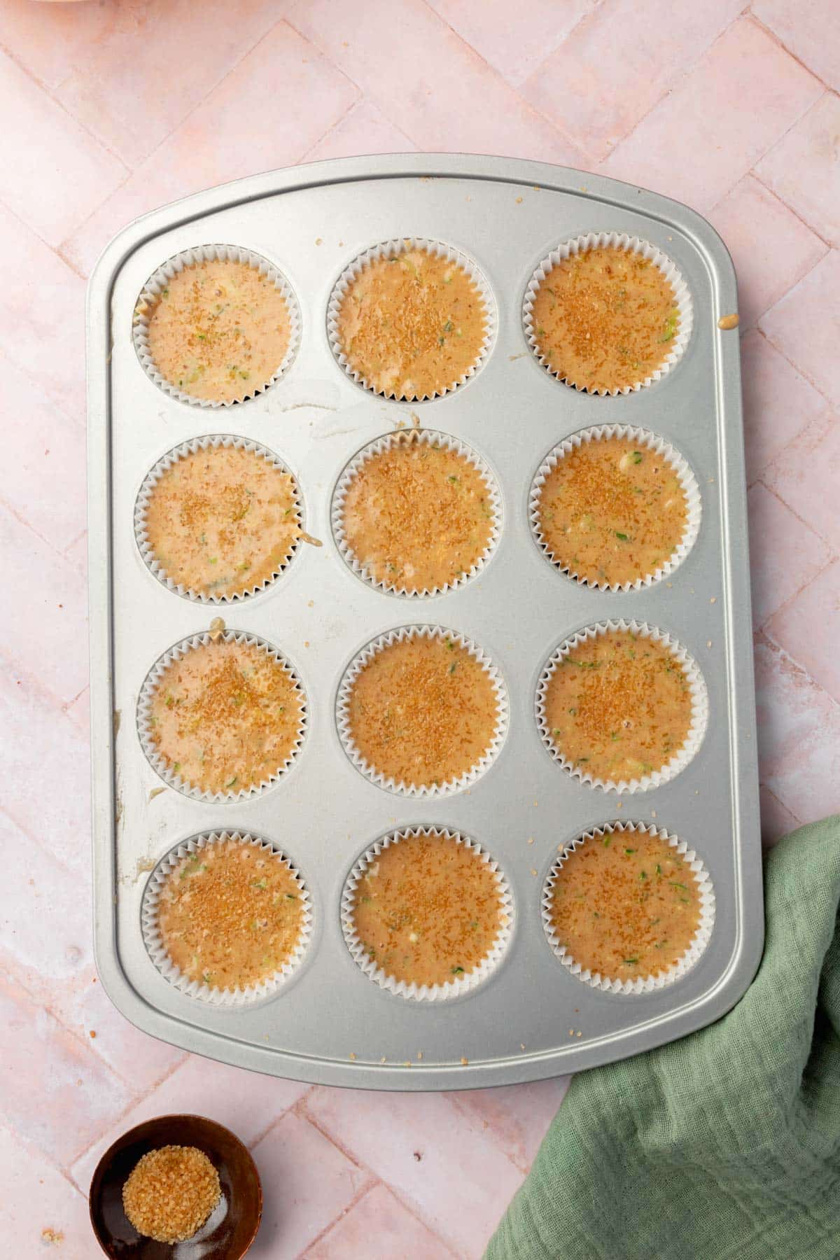An overhead view of a muffin tin filled with gluten-free zucchini muffin batter.