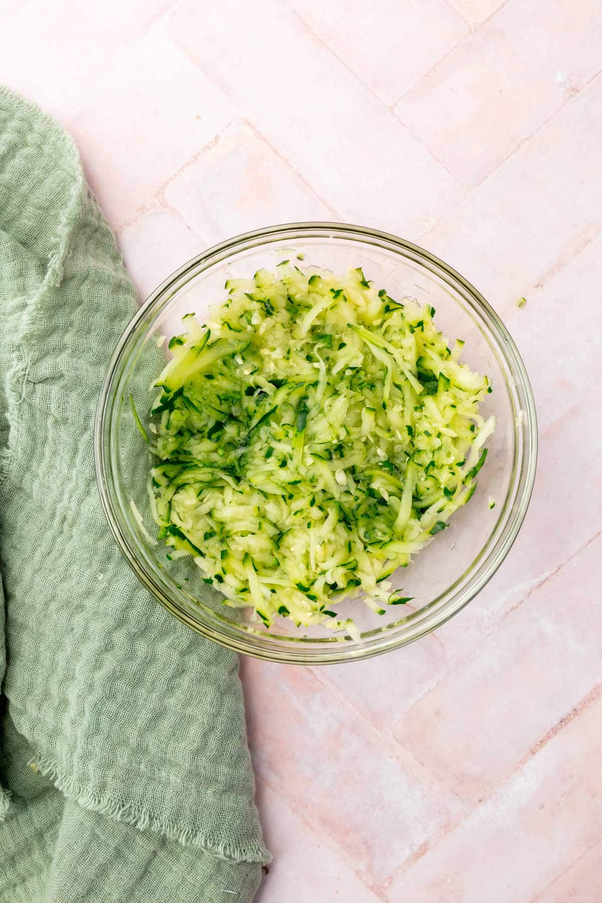 A glass bowl of shredded zucchini in it.