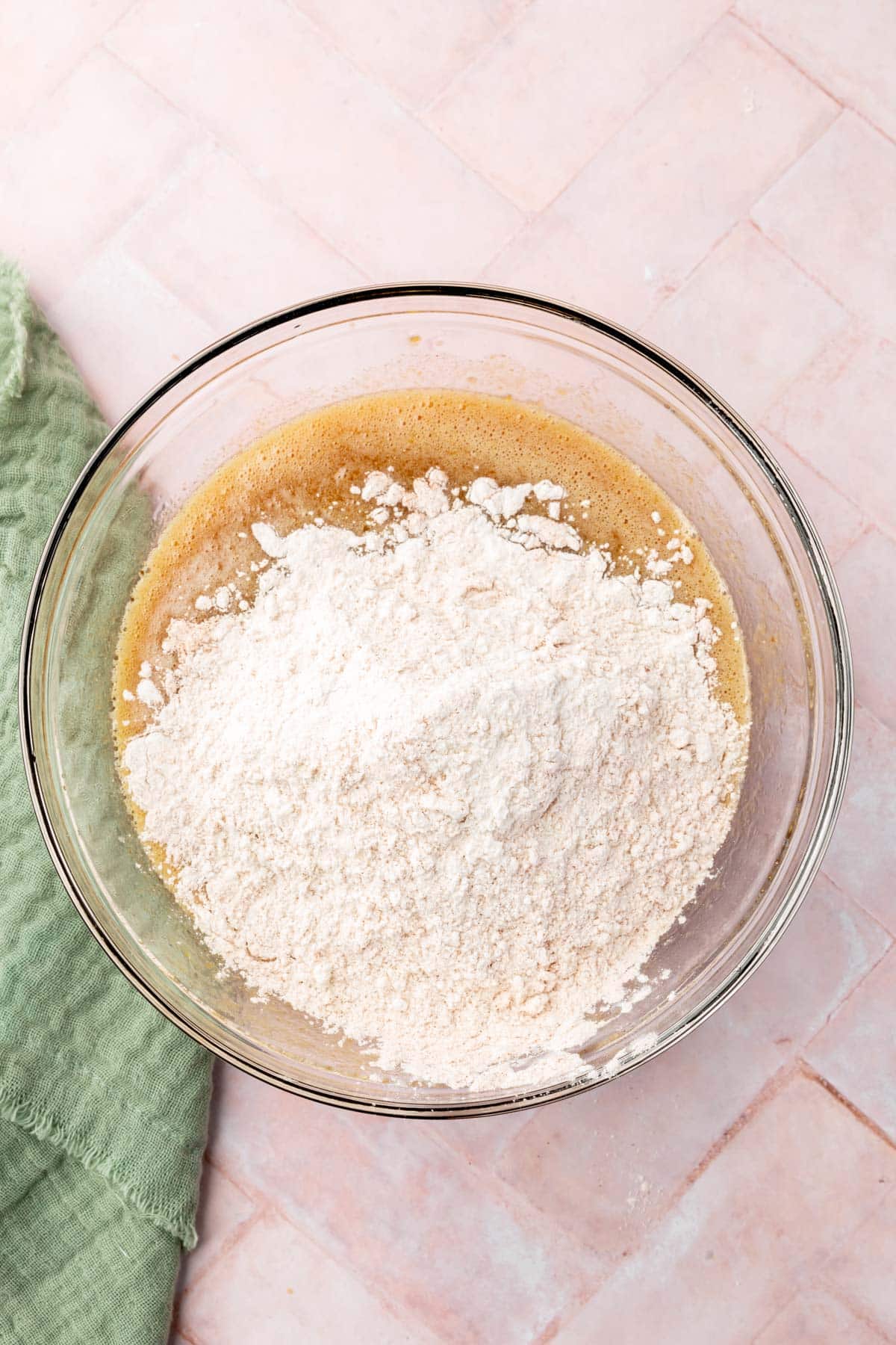 A glass mixing bowl with gluten-free flour and wet ingredients in it.