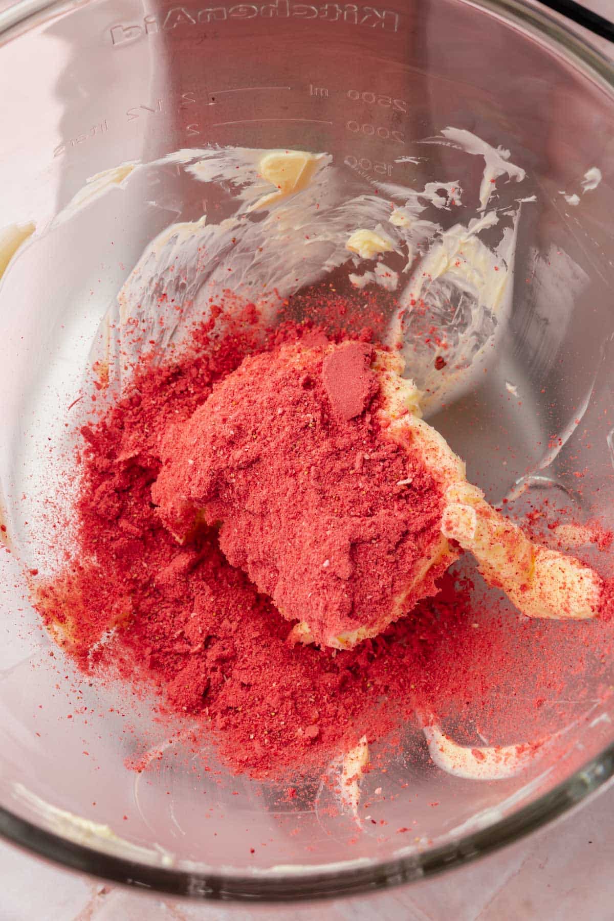 Powdered freeze-dried strawberries and butter in the bowl of a stand mixer.