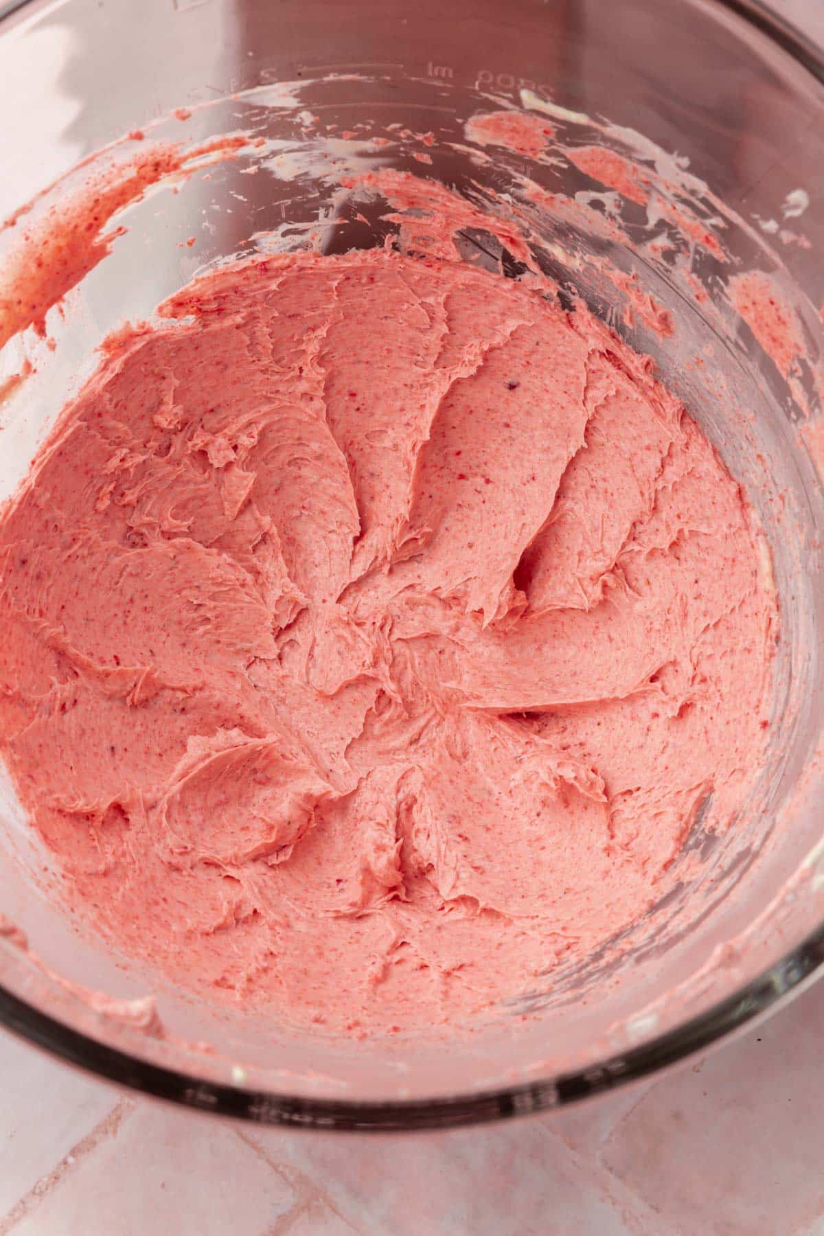 Creamed butter and freeze-dried strawberries in the bowl of a stand mixer.