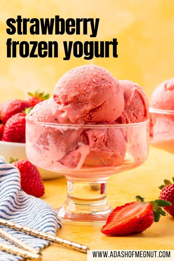 A glass footed bowl with scoops of strawberry frozen yogurt in it on a yellow table.
