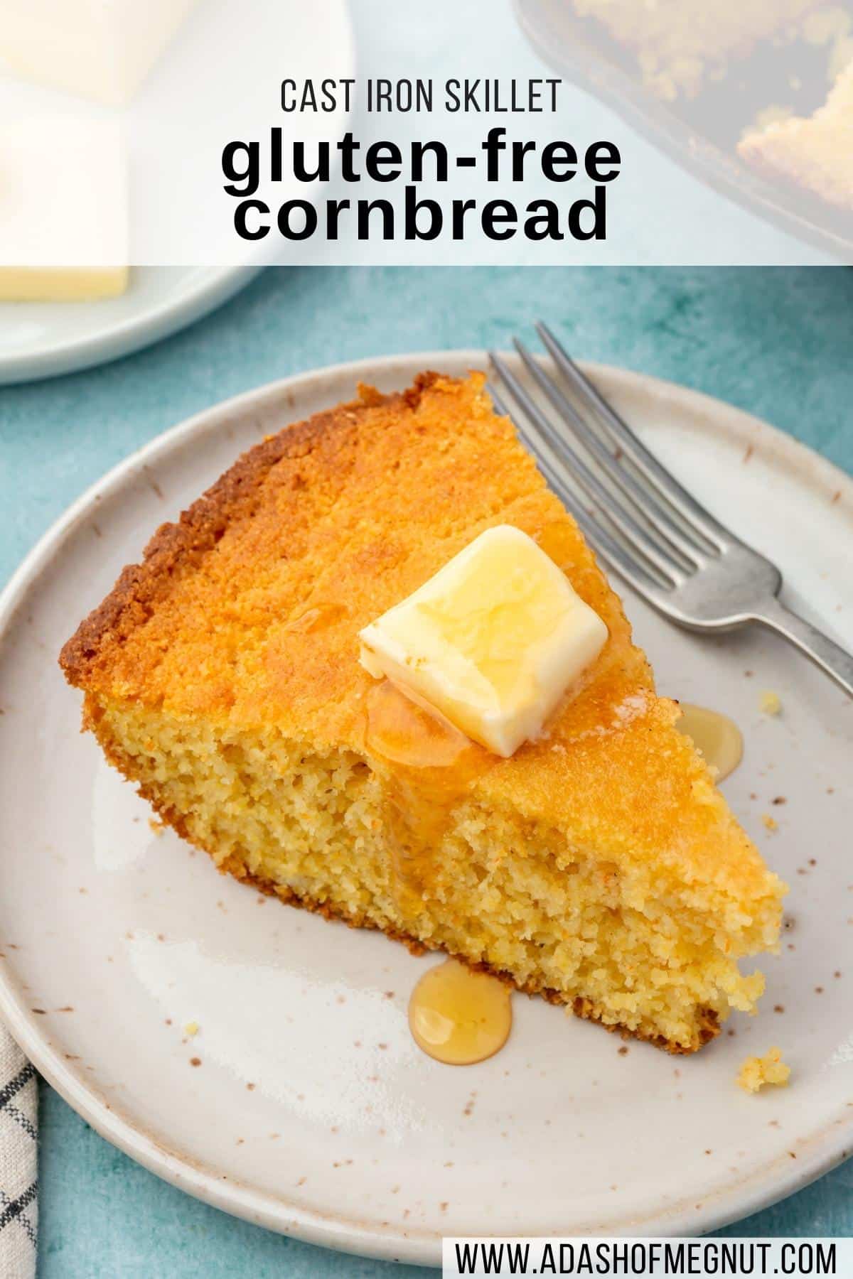A wedge of gluten-free cornbread on a small plate topped with a pat of butter and a drizzle of honey with a fork next to it.