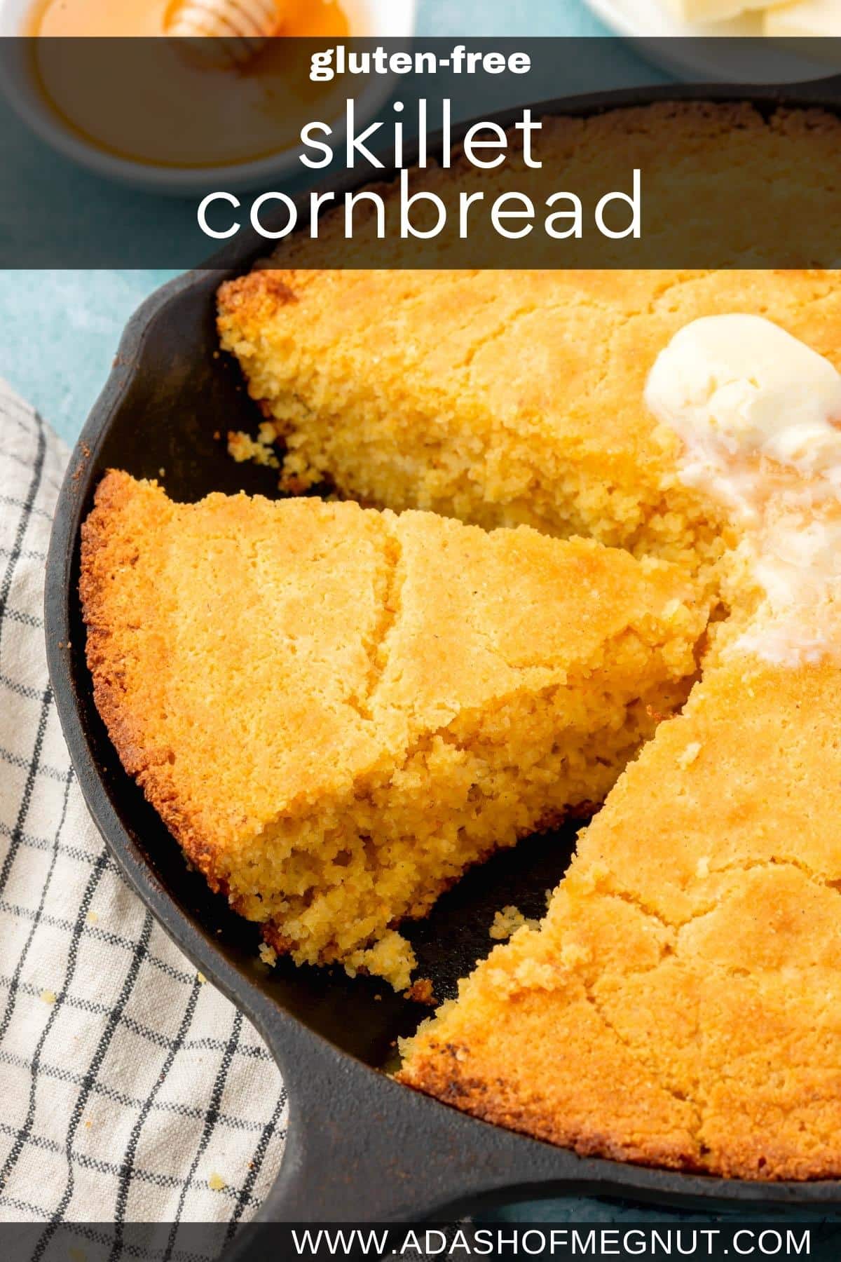 A slice of cornbread in a cast iron skillet that has been cut from the remaining whole cornbread.