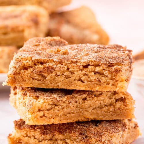 A stack of three gluten-free snickerdoodle bars on a pink table.