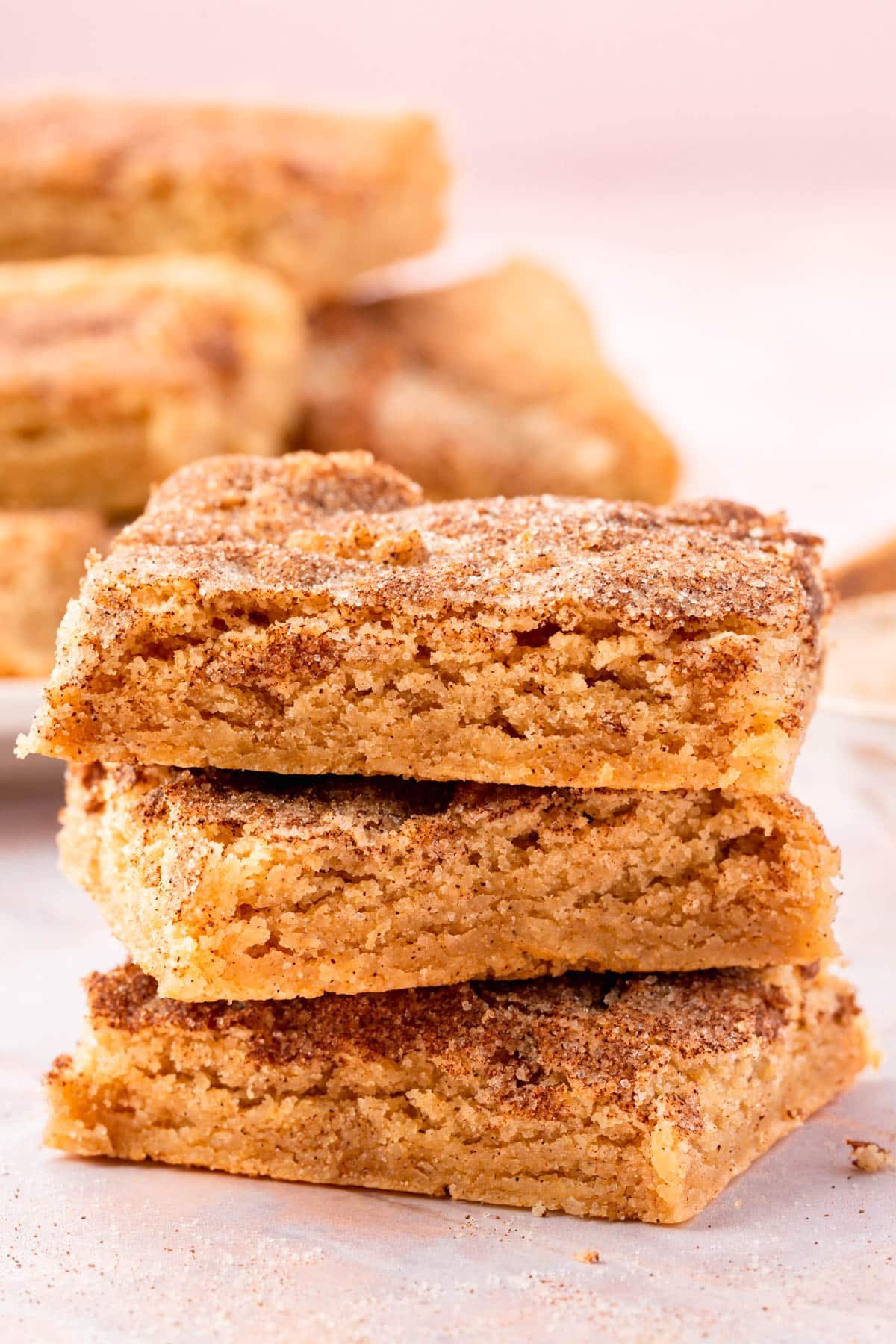 A stack of three gluten-free snickerdoodle bars on a pink table.