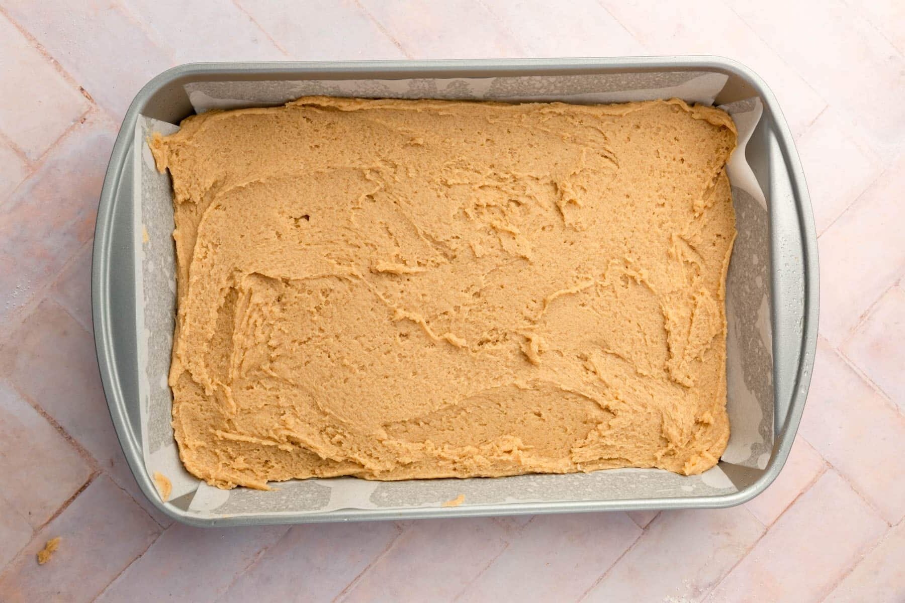 Gluten-free snickerdoodle cookie dough in a rectangle baking pan.