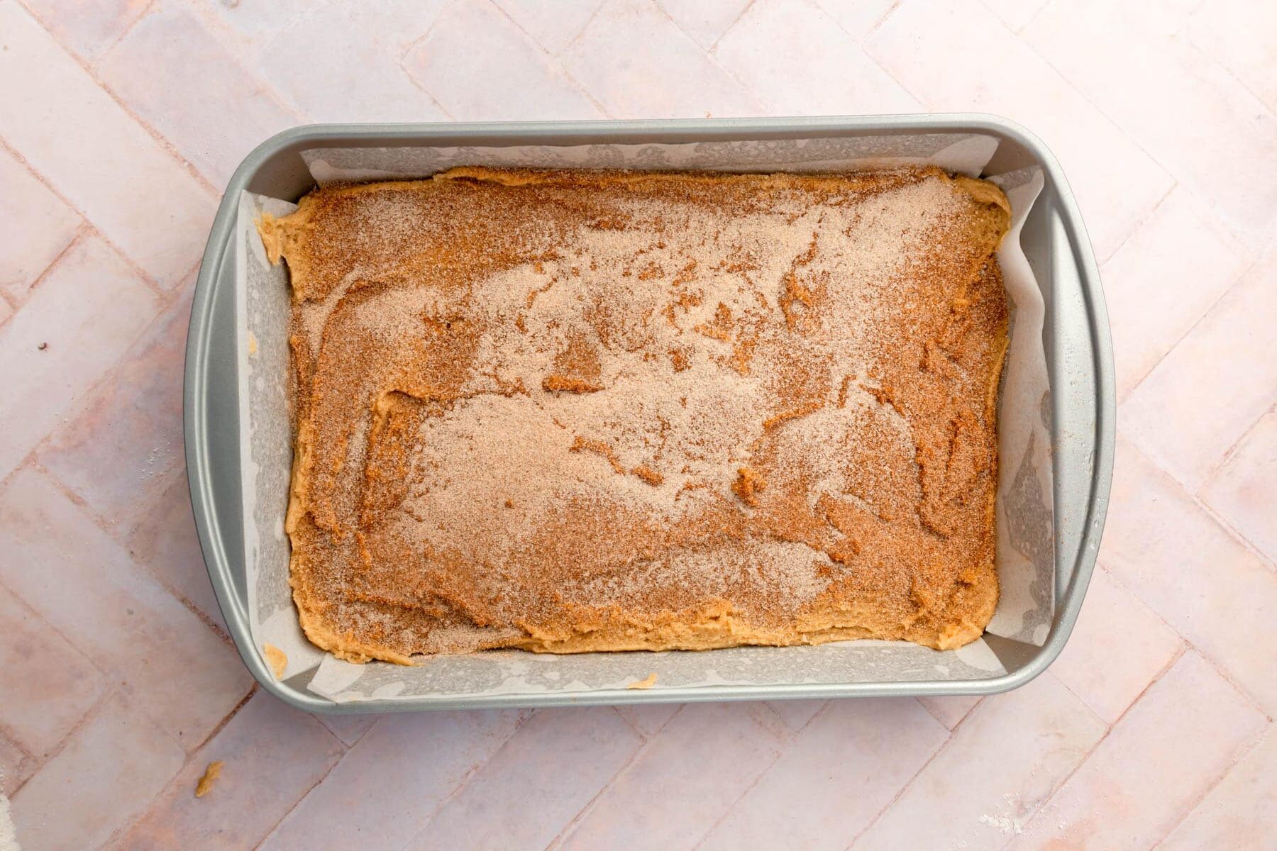 An overhead view of snickerdoodle bars in a rectangle baking dish lined with parchment paper.