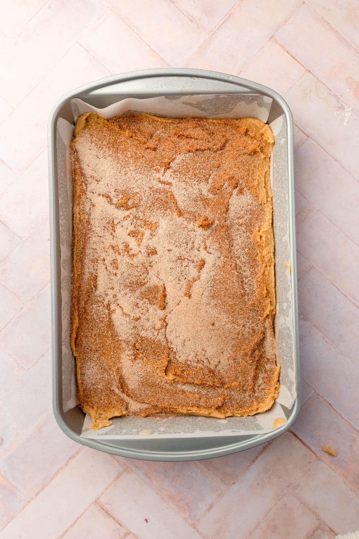 An overhead view of snickerdoodle bars in a rectangle baking dish lined with parchment paper.