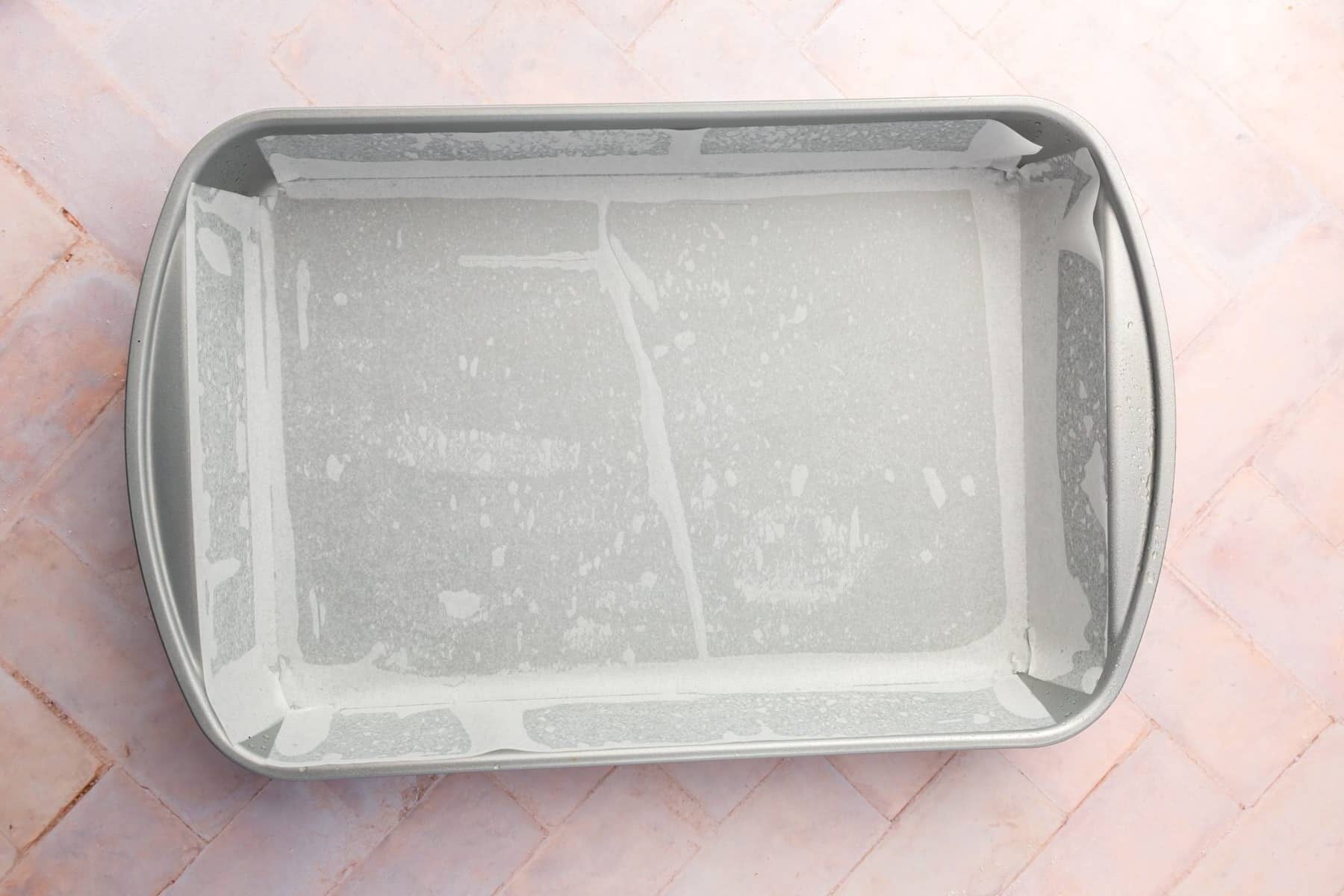 A metal rectangular baking pan that is lined with parchment paper.