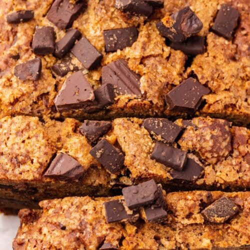 A closeup of a loaf of gluten-free vegan chocolate chunk banana bread that has been partially sliced.