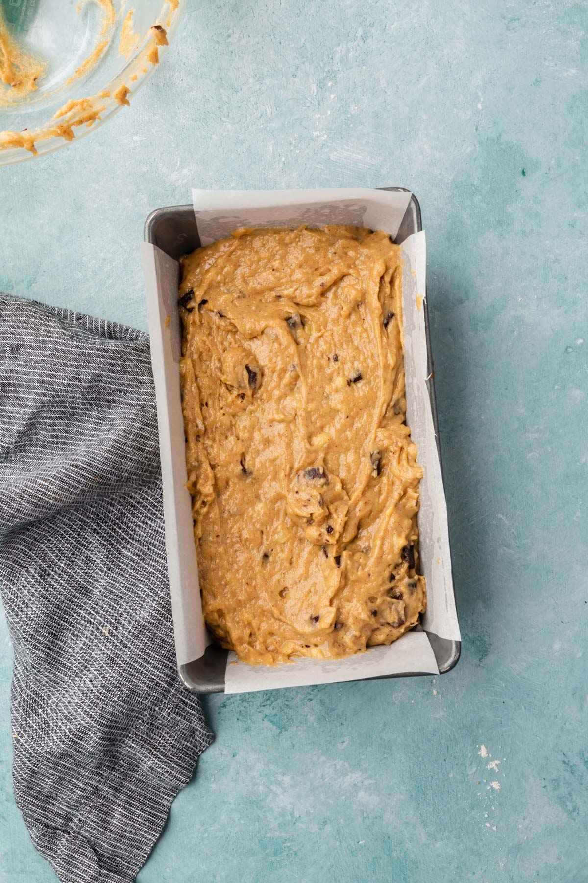 A metal loaf pan with gluten-free banana bread batter before baking.