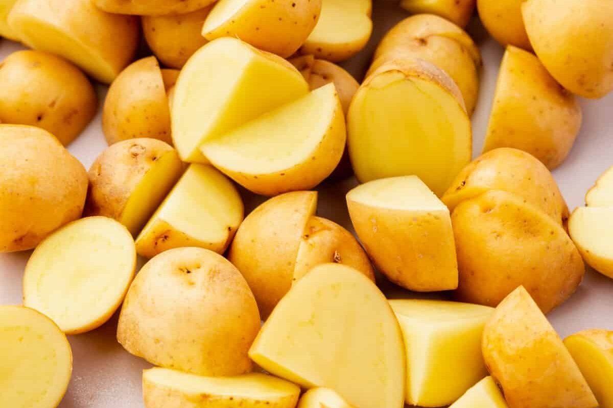 A closeup of baby yukon gold potatoes that have been sliced in half on a cutting board.