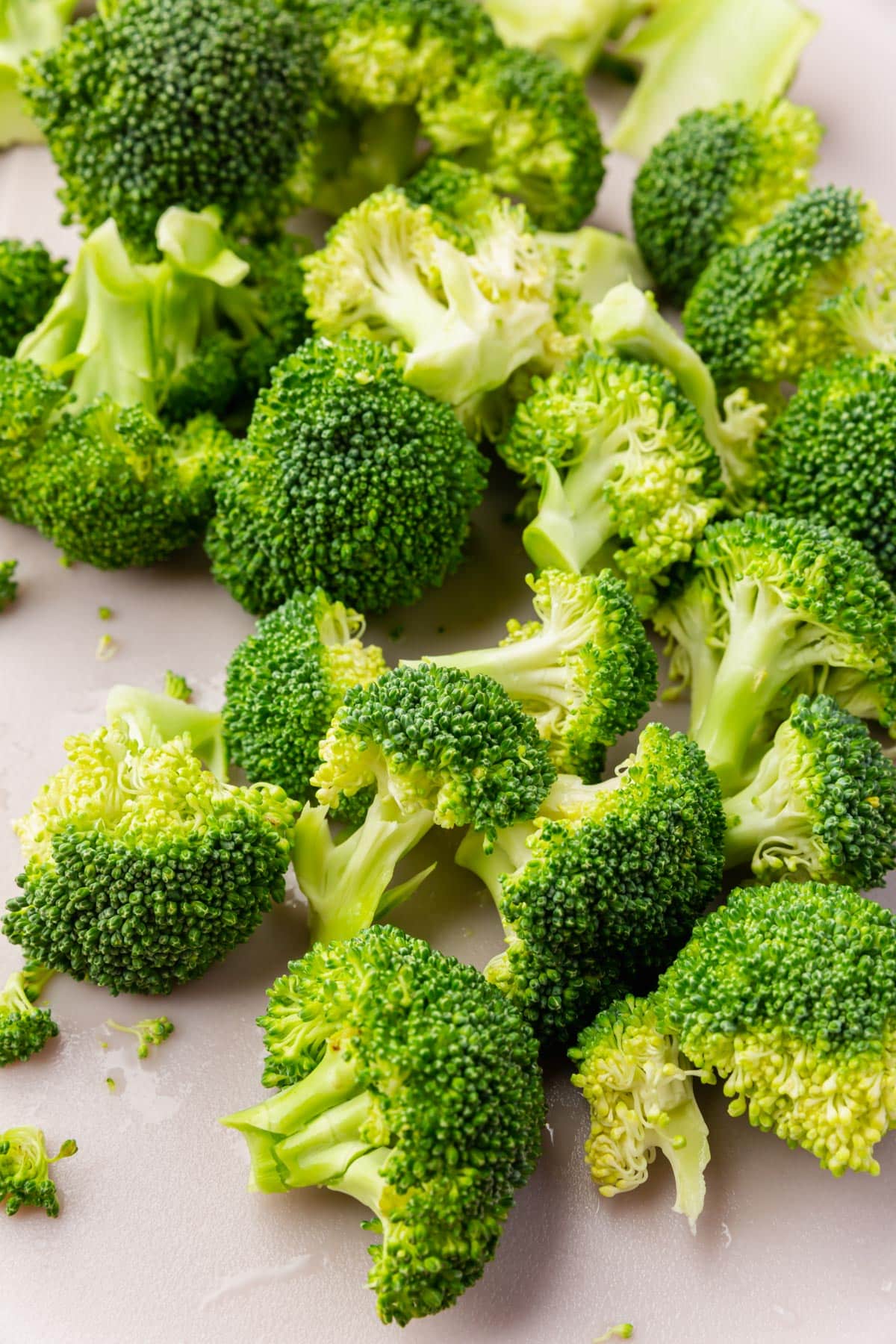 Broccoli florets that have been cut into smaller pieces on a cutting board.