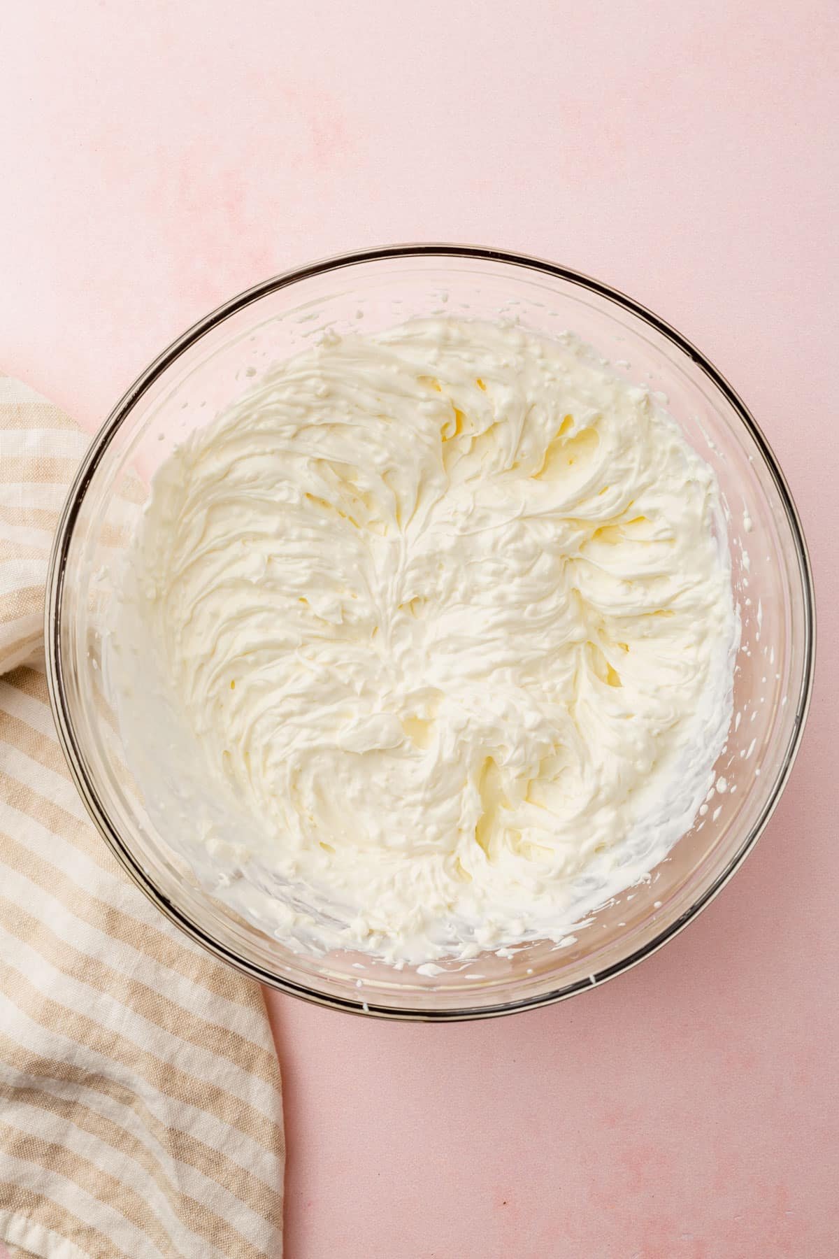 A glass mixing bowl with a cream cheese and sour cream mixture that has been blended together.