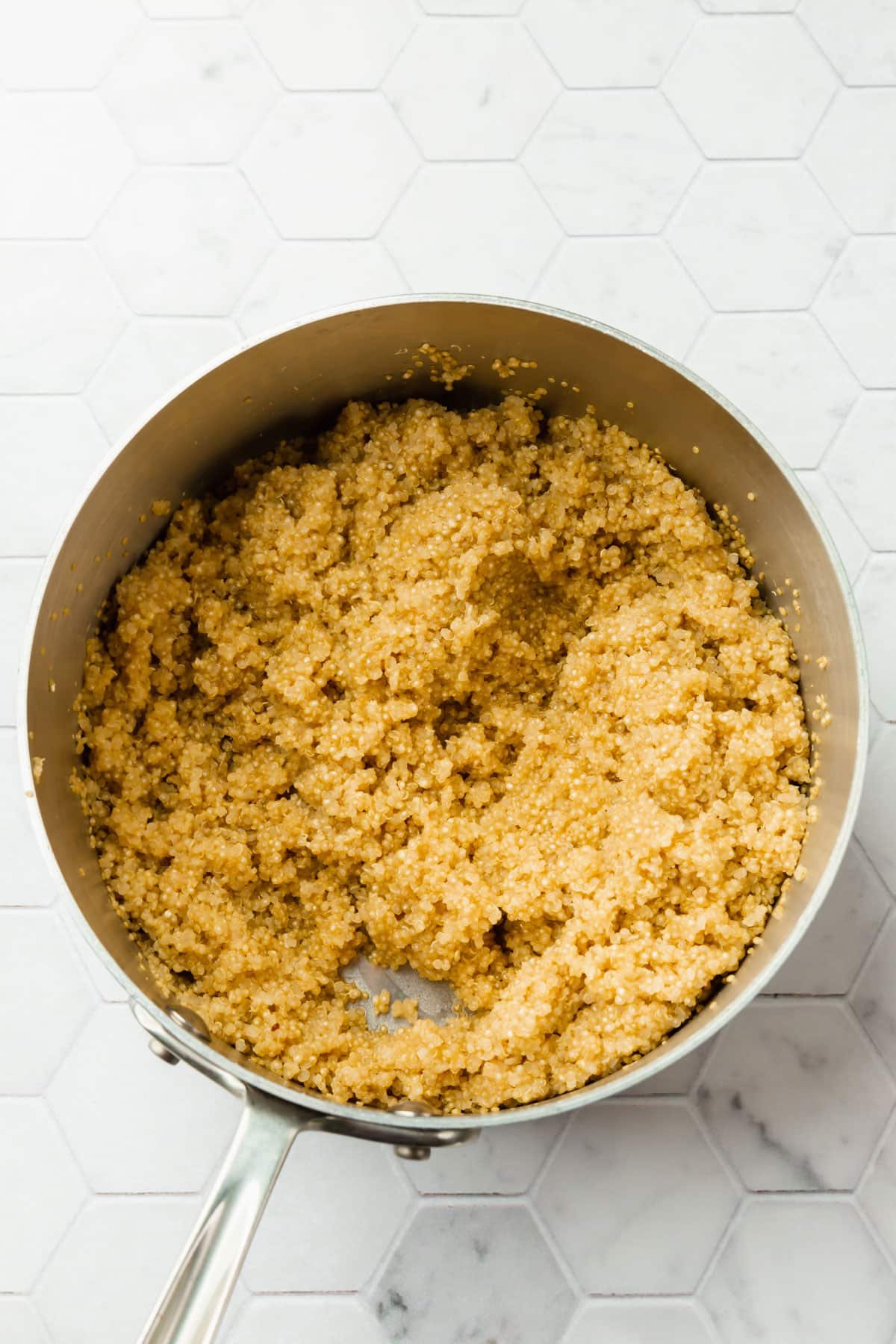 A stainless steel pot filled with cooked quinoa.