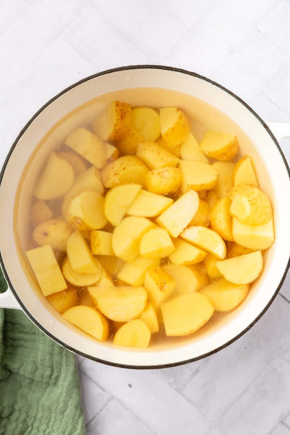 A large dutch oven filled with yukon gold potato cubes and water.