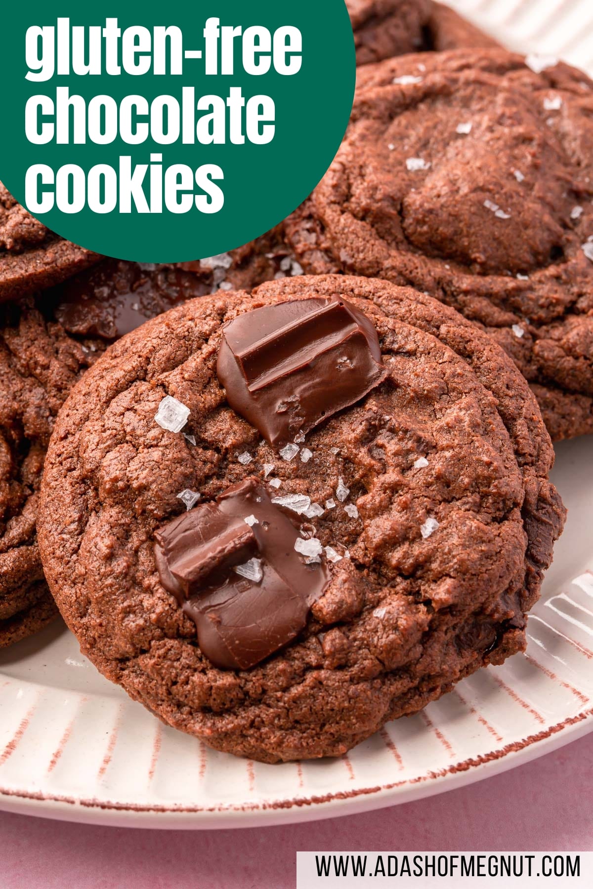 A closeup of a pile of gluten-free chocolate chunk cookies topped with flaky Maldon salt.