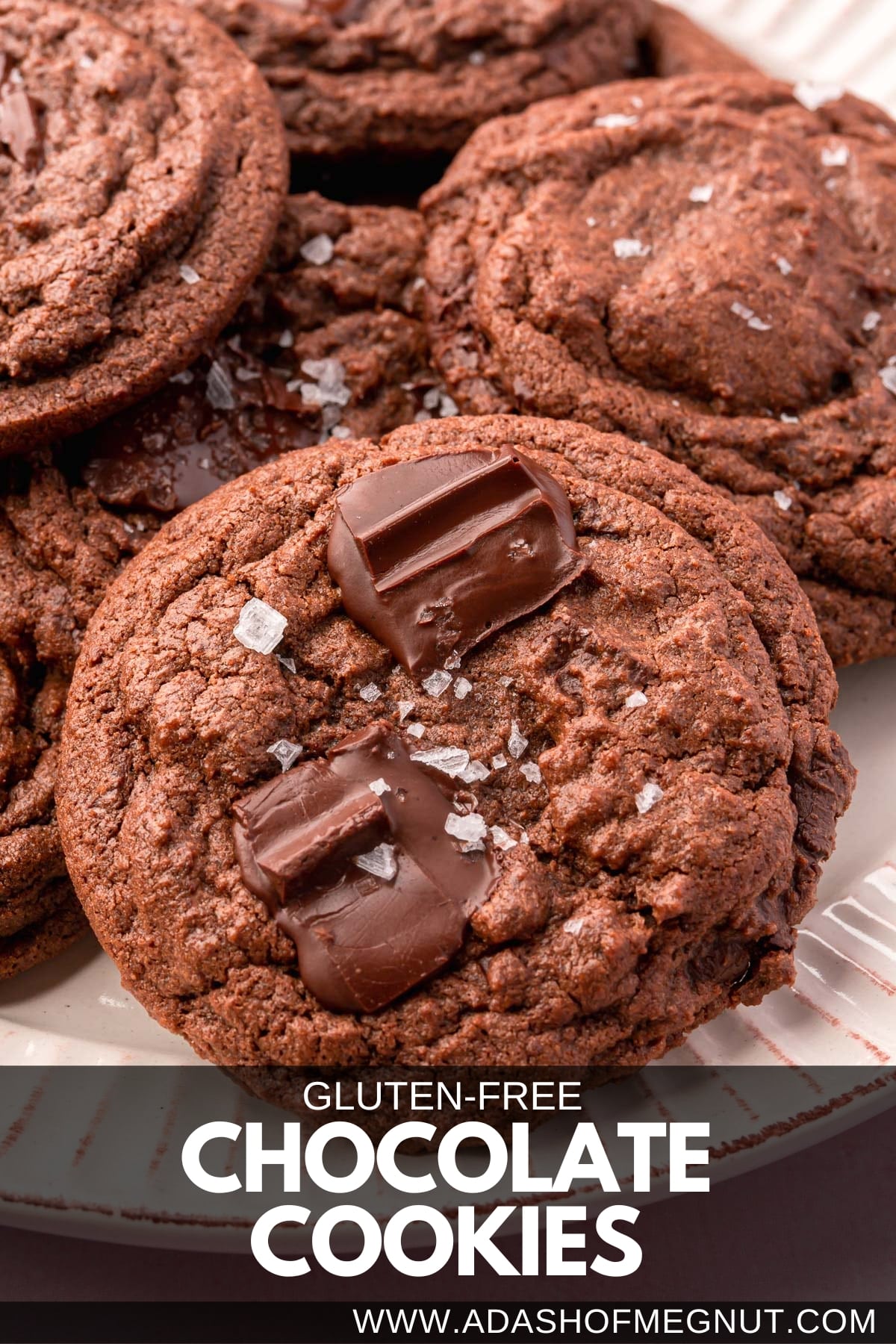 A closeup of a pile of gluten-free chocolate chunk cookies topped with flaky Maldon salt.
