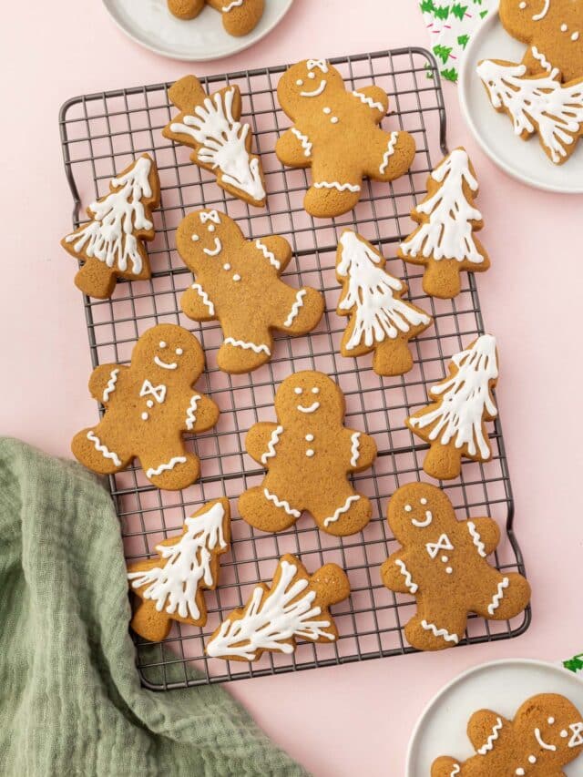 A cooling rack with gluten-free gingerbread men and gingerbread christmas tree cookies on it frosted with white royal icing.