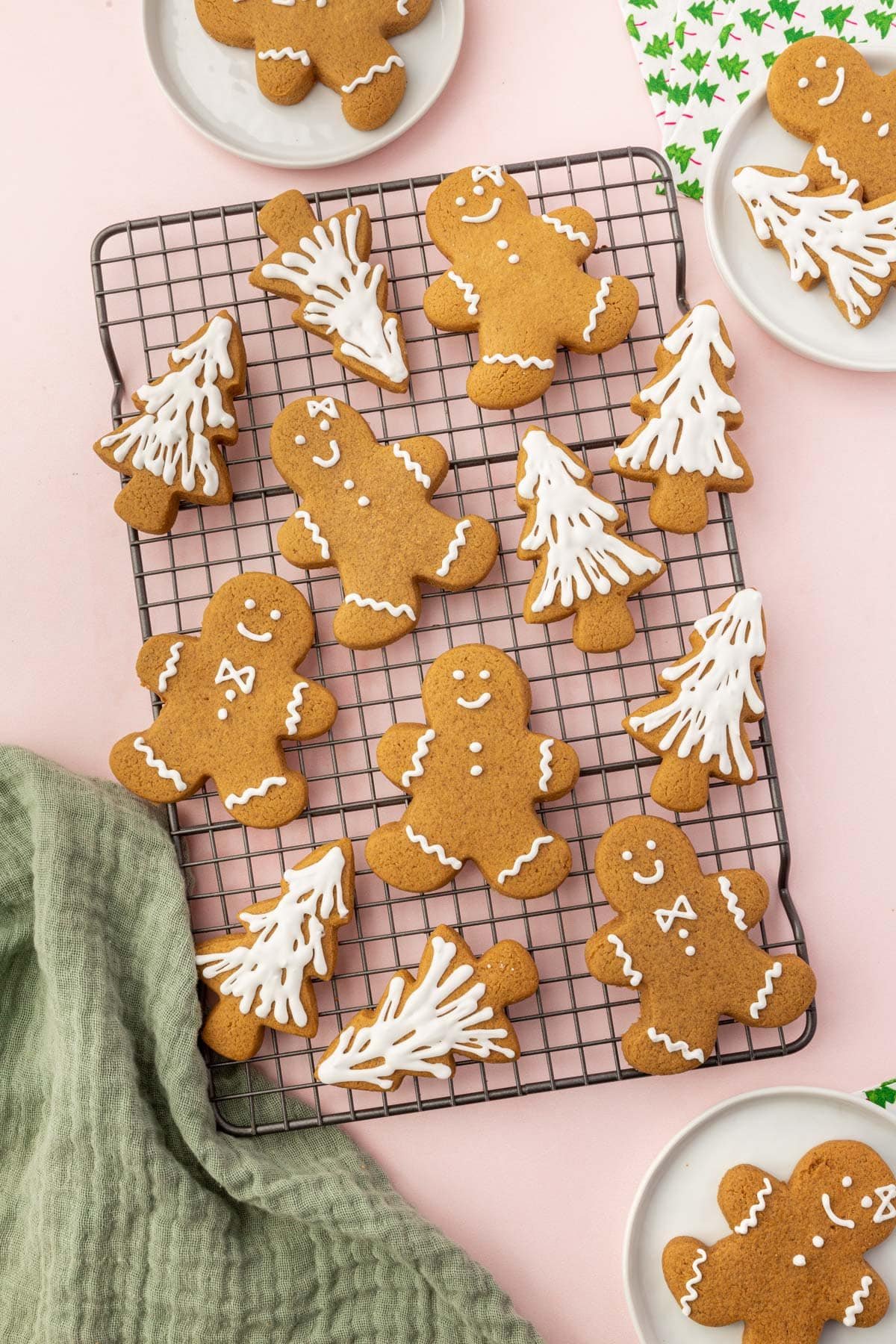 A cooling rack with gluten-free gingerbread men and gingerbread christmas tree cookies on it frosted with white royal icing.