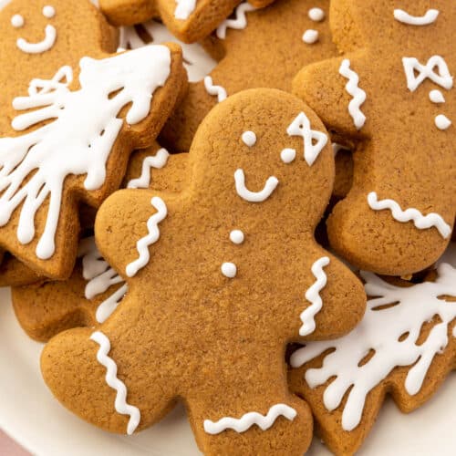 A plate of gluten-free gingerbread cookies shaped like Christmas trees and gingerbread men decorated with royal icing.