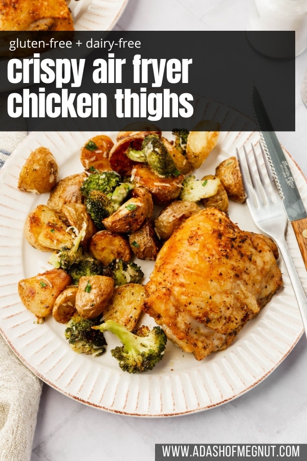 A dinner plate with a single crispy chicken thigh, a side of roasted baby potatoes and broccoli, and a fork and knife.