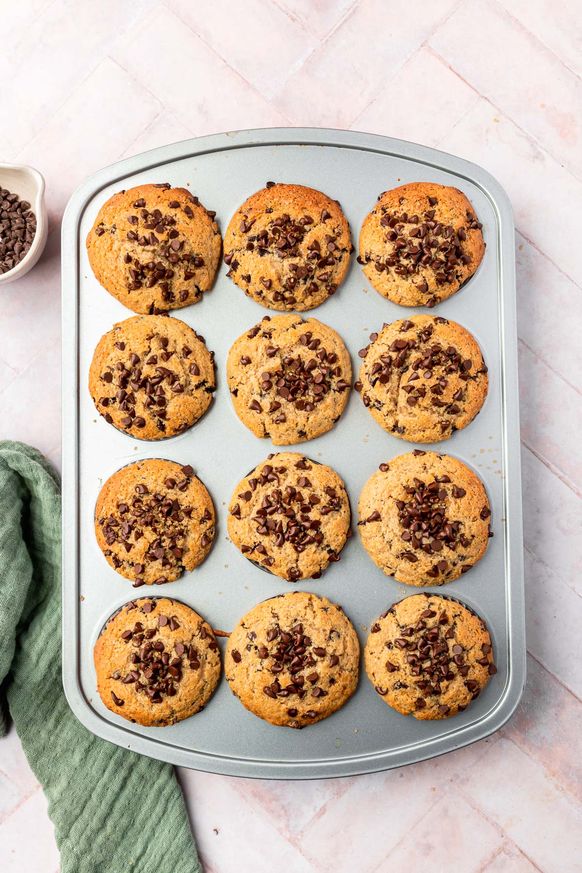 A 12-cup muffin tray filled with baked gluten-free chocolate chip muffins.
