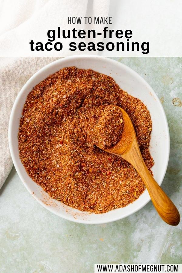 A bowl of gluten-free taco seasoning blend being mixed up by a small wooden spoon on a green marble table.