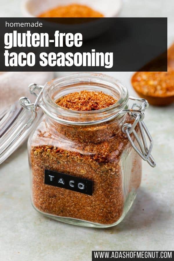 Gluten-free taco seasoning in a glass jar with a black label that says "TACO" on a green marble table with a text overlay.