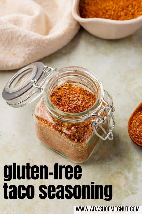 Gluten-free taco seasoning in a glass jar on a green marble table with a text overlay.
