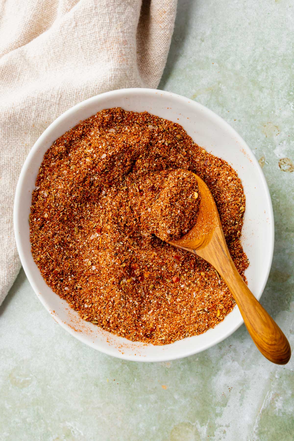 A bowl of gluten-free taco seasoning with a wooden spoon and a linen napkin.