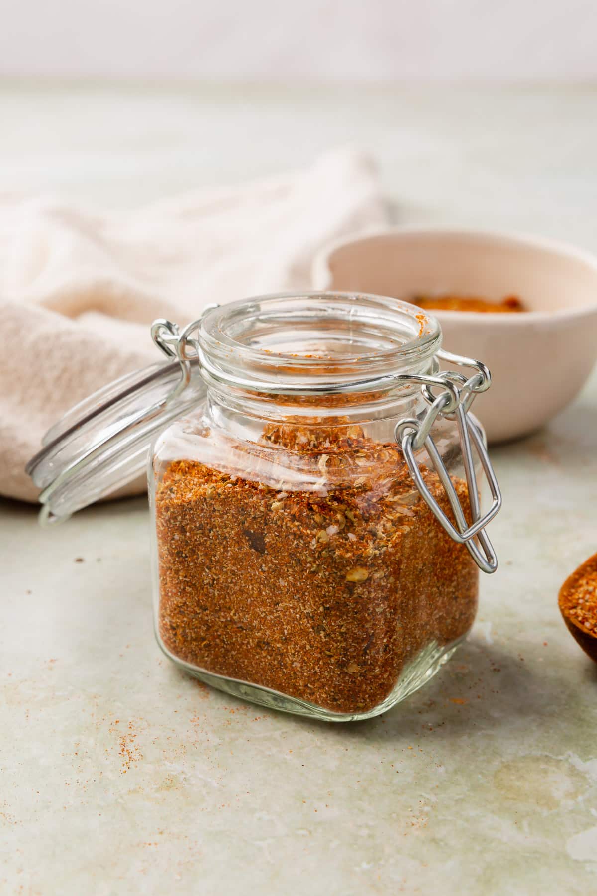 Gluten-free taco seasoning in a glass jar on a green marble table.
